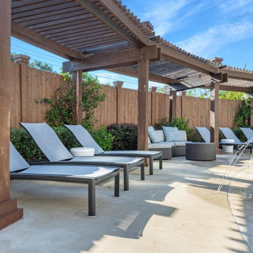 a pool with benches and a covered patio